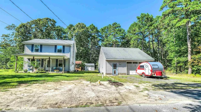 a front view of a house with a garden and trees
