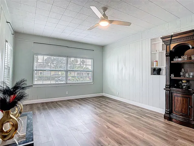 a view of empty room with wooden floor and fan