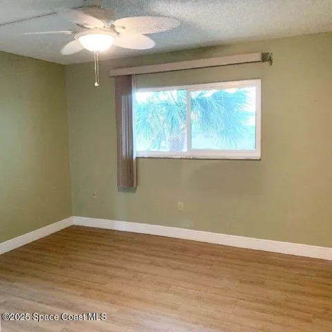 a view of a big room with wooden floor and windows