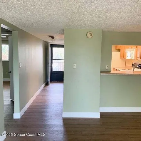 a view of a hallway with wooden floor and a bathroom