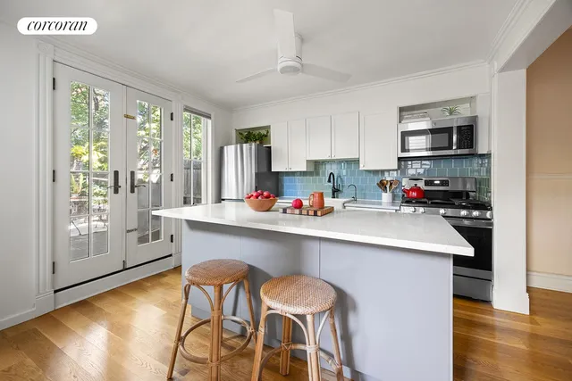 a kitchen with stainless steel appliances a sink a stove a refrigerator cabinets and a dining table with wooden floor