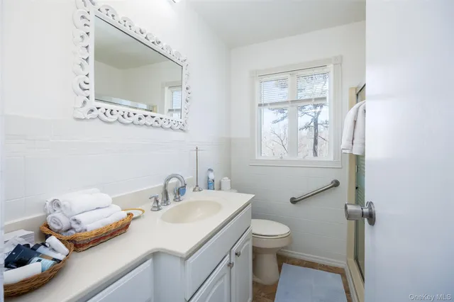 a bathroom with a granite countertop sink toilet and mirror