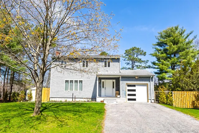 a front view of a house with a garden and trees