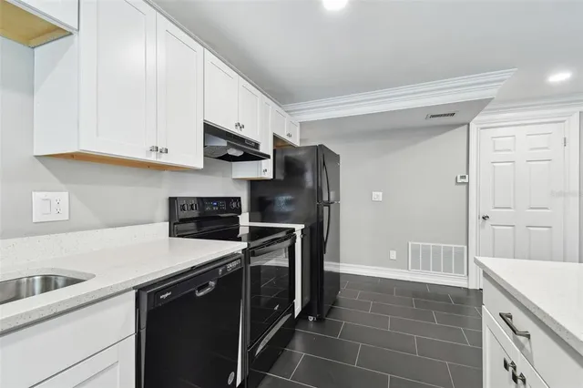 a kitchen with stainless steel appliances granite countertop white cabinets and a sink