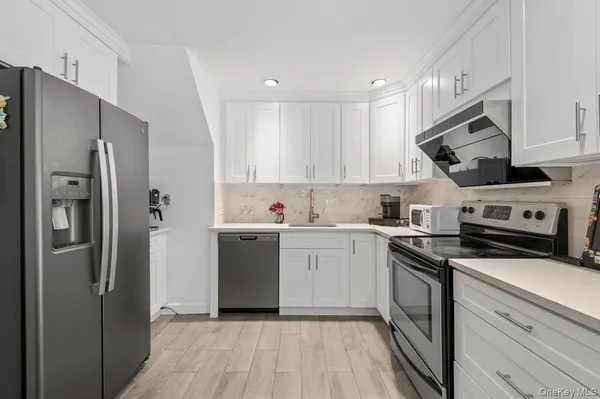 a kitchen with a sink stainless steel appliances and white cabinets