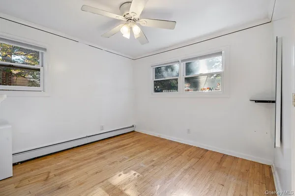a view of empty room with wooden floor and fan