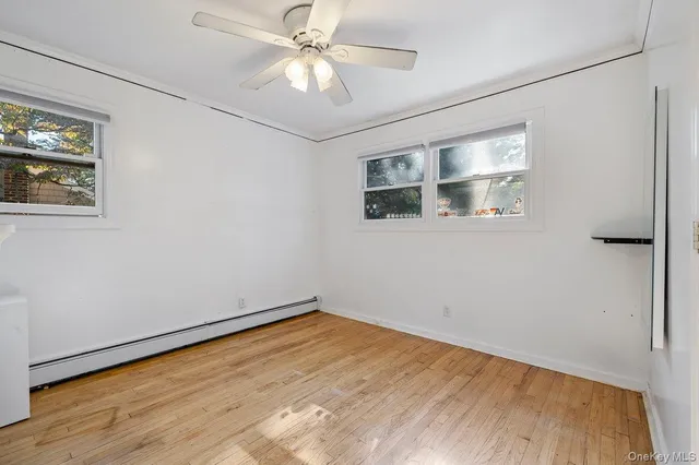 a view of empty room with wooden floor and fan