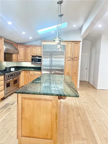 a large kitchen with stainless steel appliances granite countertop a granite counter tops and a wooden floors