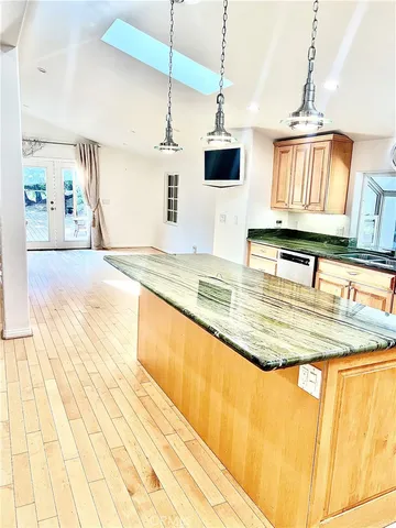 a kitchen with kitchen island granite countertop a sink a counter top space cabinets and stainless steel appliances