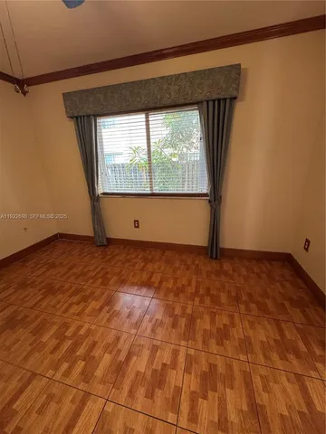 an empty room with wooden floor and chandelier