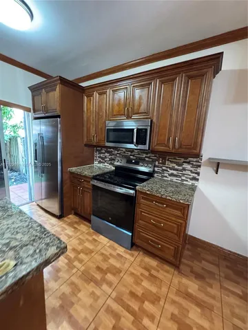 a kitchen with granite countertop a stove a sink and a refrigerator
