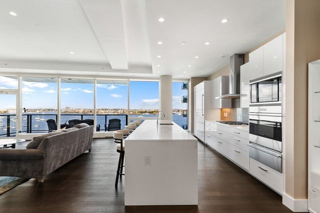 a view of living room kitchen with stainless steel appliances kitchen island stove and living room