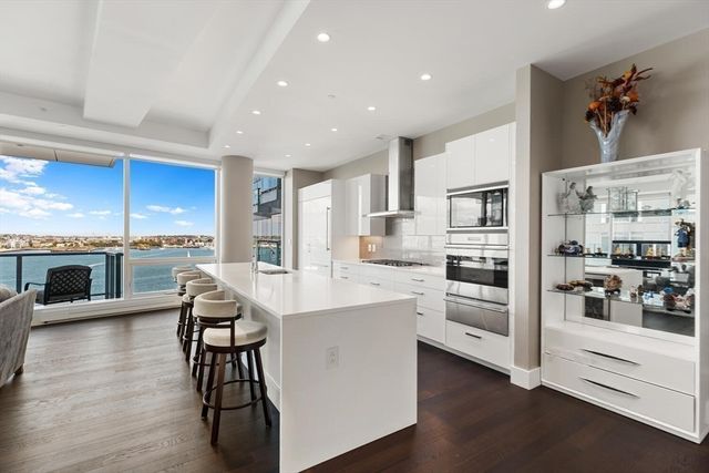 a kitchen with stainless steel appliances a white table chairs refrigerator and sink