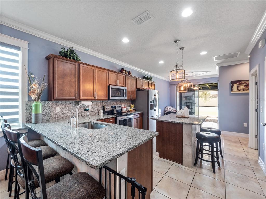 3570 Southern Cross Loop Kissimmee, FL 34744 - Photo 2 of 36 a kitchen with granite countertop kitchen island stainless steel appliances a table chairs sink and cabinets