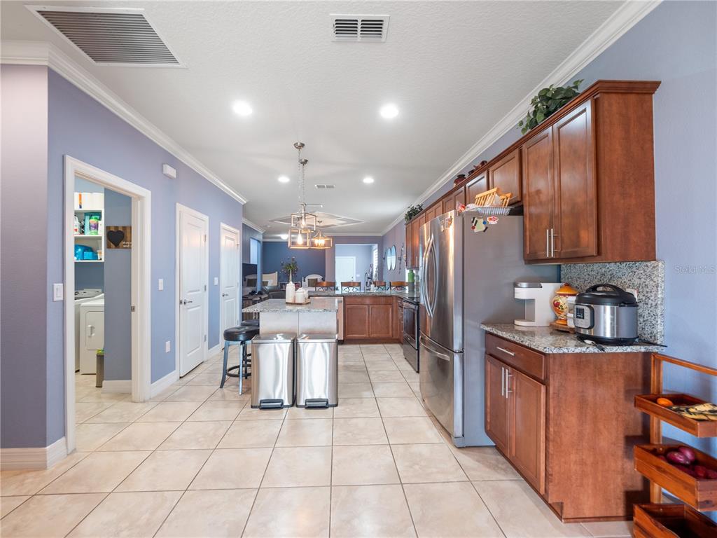 3570 Southern Cross Loop Kissimmee, FL 34744 - Photo 7 of 36 a kitchen with stainless steel appliances kitchen island granite countertop a refrigerator a sink a stove and island