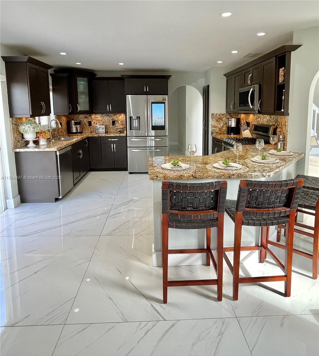 15542 Southwest 148th Terrace Miami, FL 33196 - Photo 14 of 38 a kitchen with stainless steel appliances kitchen island granite countertop a table and chairs in it