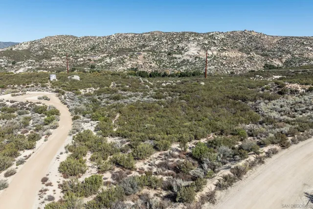 a view of a dry field with mountains in the background