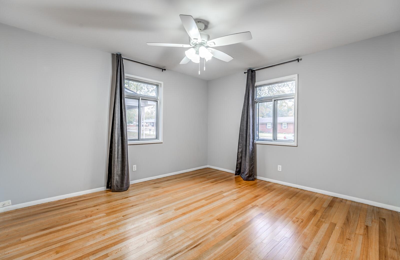 512 Fleda Road Memphis, TN 38120 - Photo 21 of 26 an empty room with wooden floor chandelier fan and windows
