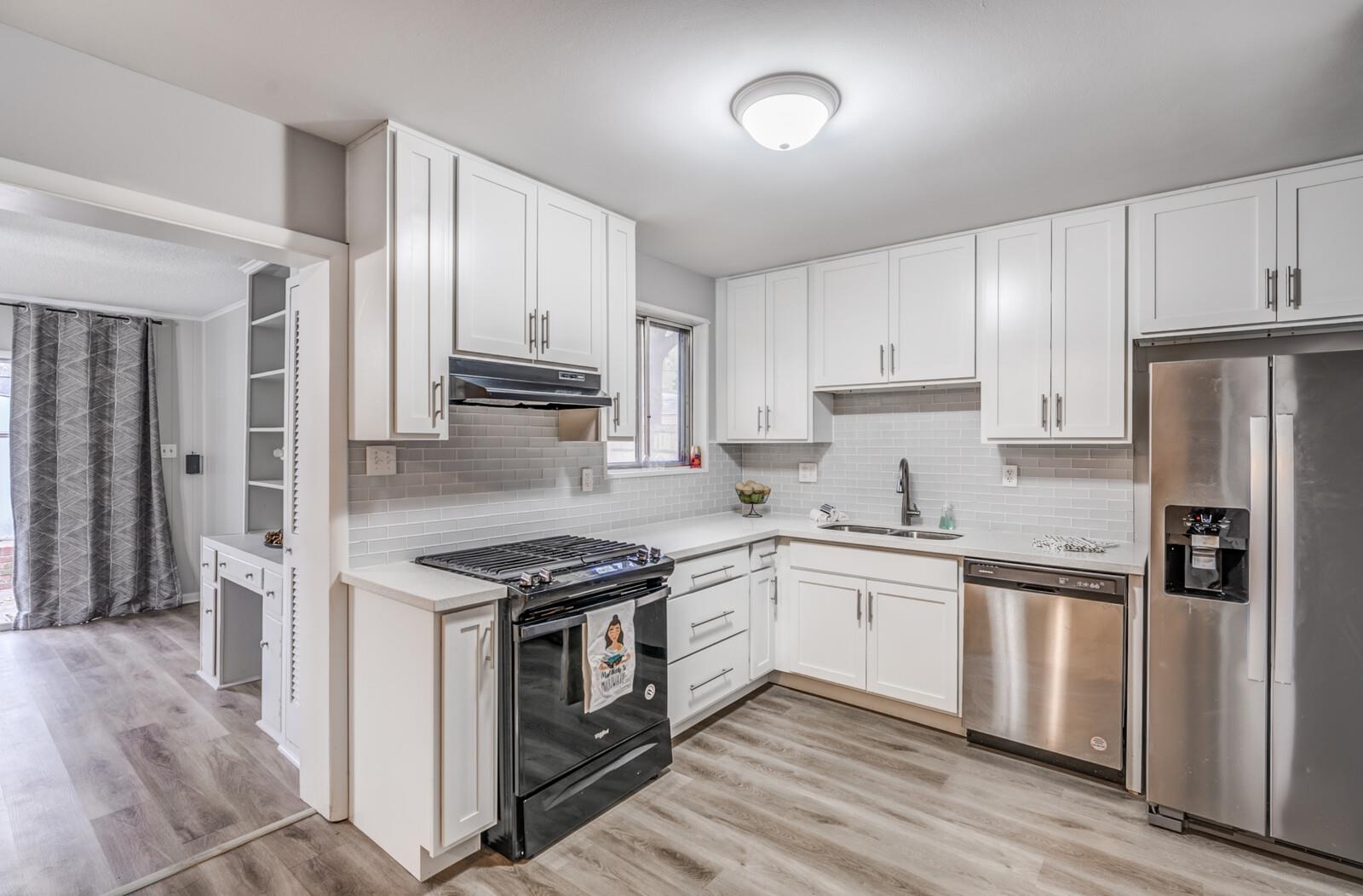 512 Fleda Road Memphis, TN 38120 - Photo 9 of 26 a kitchen with stainless steel appliances granite countertop a stove top oven a refrigerator and white cabinets with wooden floor