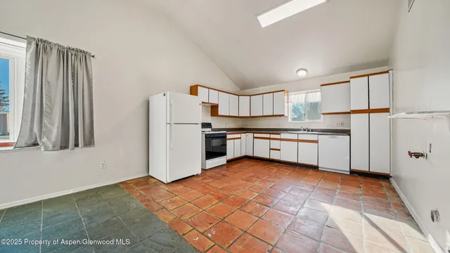 a kitchen with granite countertop white cabinets stainless steel appliances a sink and a window