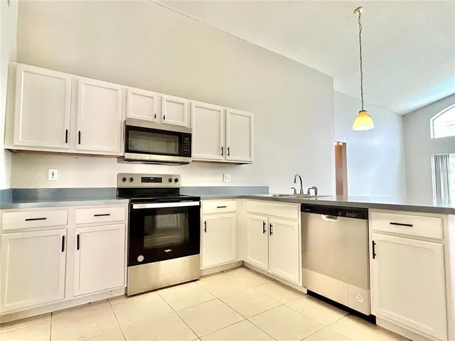 a kitchen with granite countertop white cabinets and white appliances