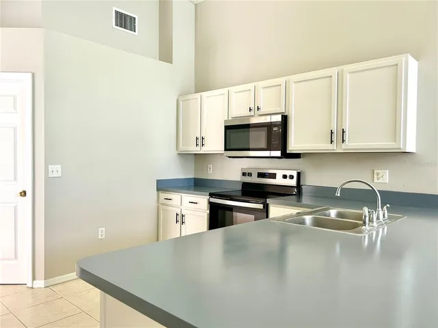 a kitchen with stainless steel appliances a stove a sink a microwave a refrigerator and cabinets