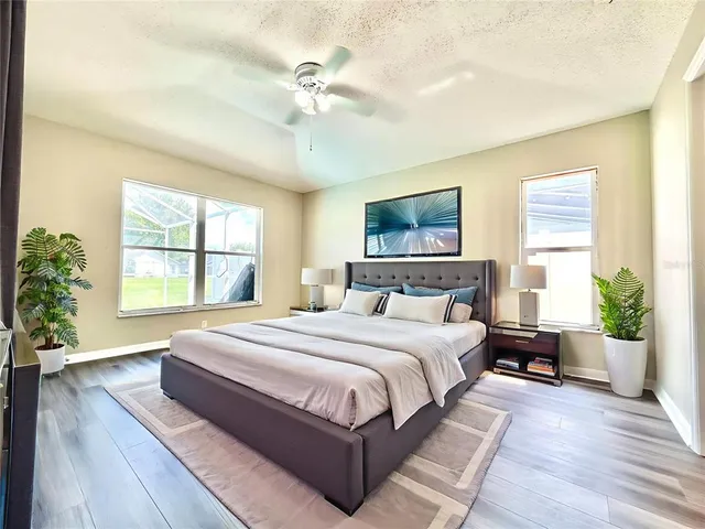 a spacious bedroom with a large bed windows and a chandelier