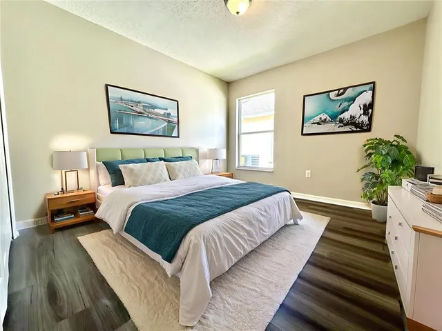 a bedroom with a bed and a potted plant on dresser