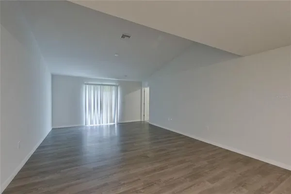 a view of an empty room with wooden floor and window