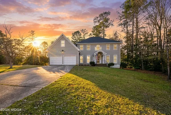 a front view of a house with a yard and trees