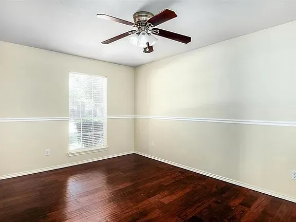 a view of an empty room with window and wooden floor