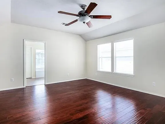 a view of an empty room with window and wooden floor