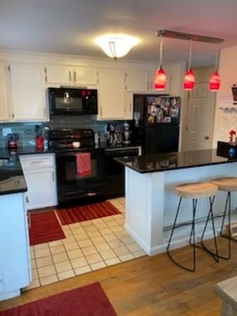 358 Sherburne Road Pelham, NH 03076 - Photo 7 of 35 a kitchen with granite countertop a stove a microwave and cabinets