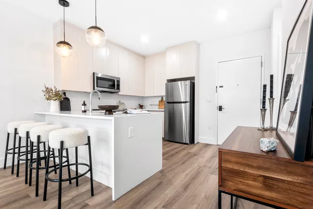 a kitchen with stainless steel appliances granite countertop a refrigerator a stove a microwave oven a sink with island and chairs