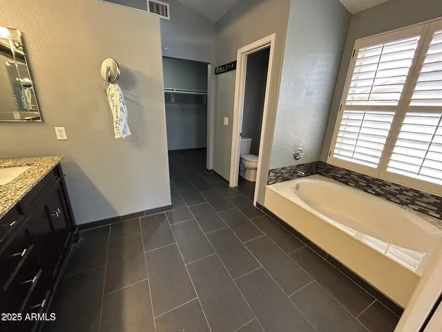a bathroom with a granite countertop sink a mirror and a bathtub