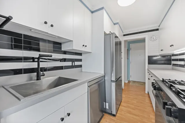 a kitchen with stainless steel appliances a sink dishwasher stove and oven with wooden floor