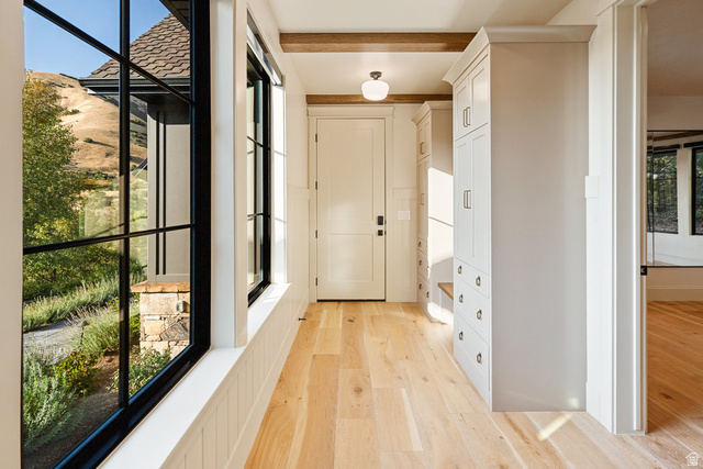 1141 South Oak Leaf Lane Springville, UT 84663 - Photo 63 of 147 Entryway featuring multiple floor-to-ceiling windows with black frames, wood-finish flooring, two built-in storage units with cabinet and drawer space, an overhead light fixture, and exposed wood beams