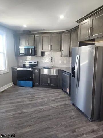 a kitchen with stainless steel appliances granite countertop a refrigerator a stove a sink and a microwave