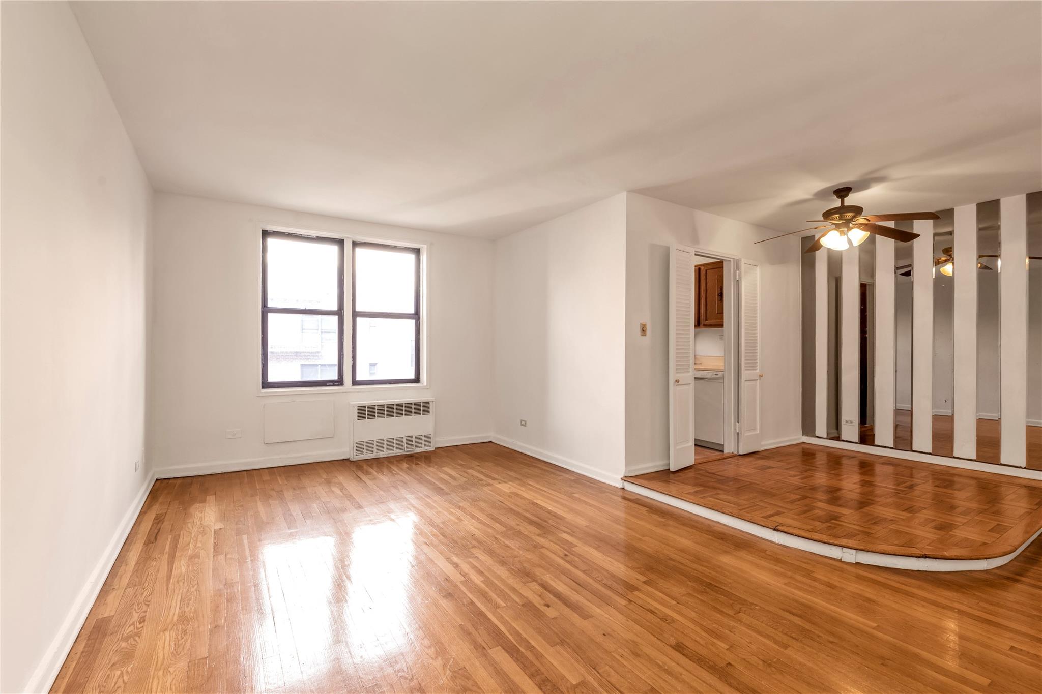 141-05 Pershing Crescent, Unit 210 Queens, NY 11435 - Photo 11 of 22 Empty room featuring ceiling fan, radiator heating unit, and light hardwood / wood-style flooring