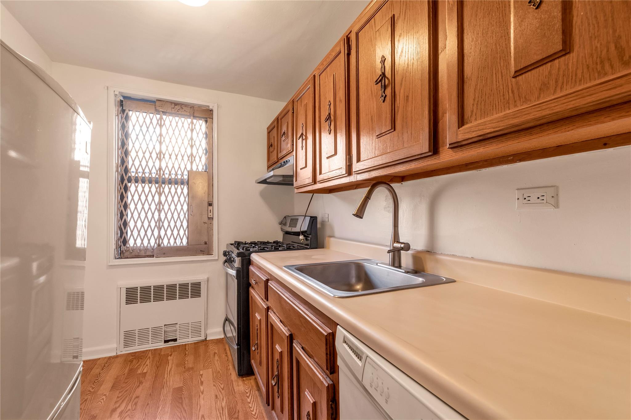 141-05 Pershing Crescent, Unit 210 Queens, NY 11435 - Photo 14 of 22 Laundry room featuring sink, radiator heating unit, and light wood-type flooring