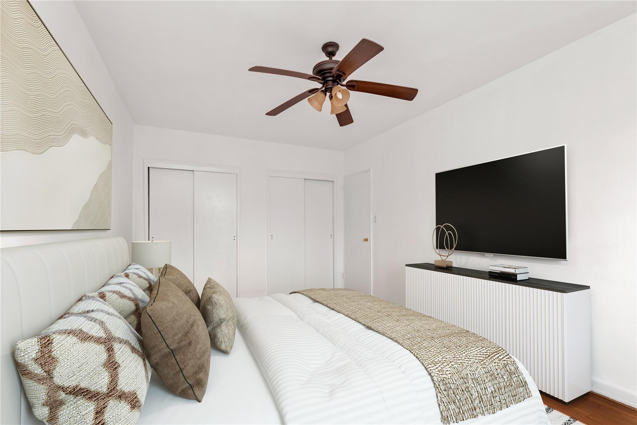 141-05 Pershing Crescent, Unit 210 Queens, NY 11435 - Photo 3 of 22 Bedroom featuring two closets, wood finished floors, and a ceiling fan