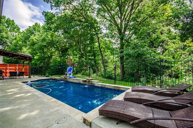 a view of swimming pool with lawn chairs and plants
