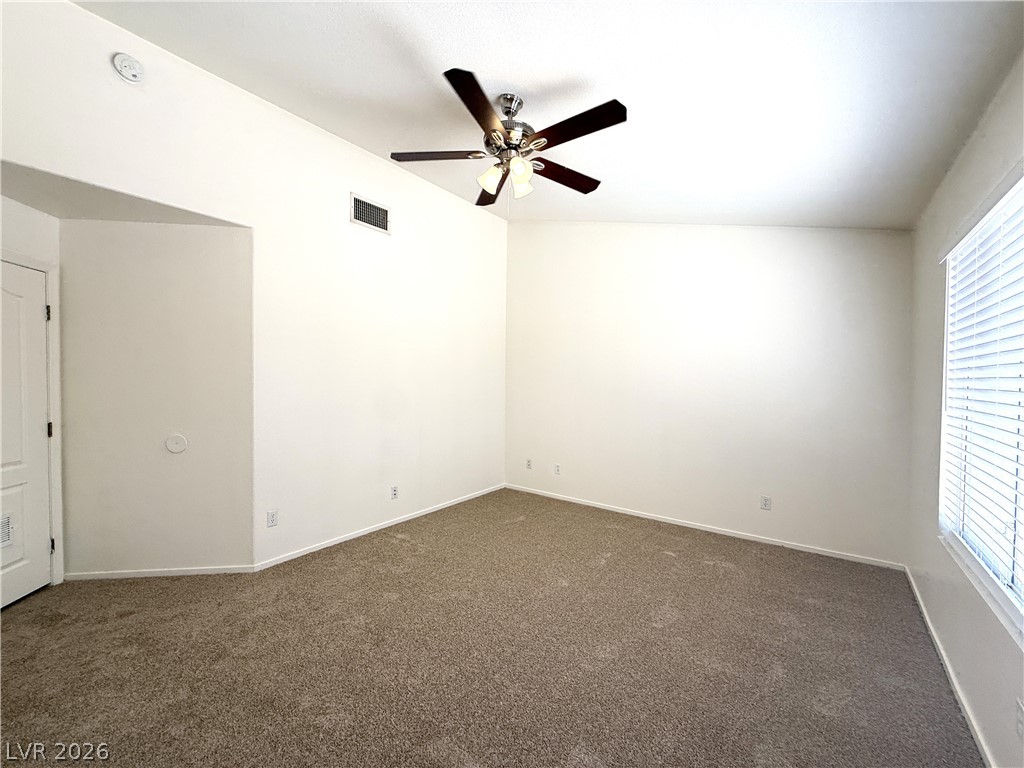 8870 Haviland Road Las Vegas, NV 89123 - Photo 7 of 22 A well-lit room offers ample space, featuring clean carpet and a functional ceiling fan.