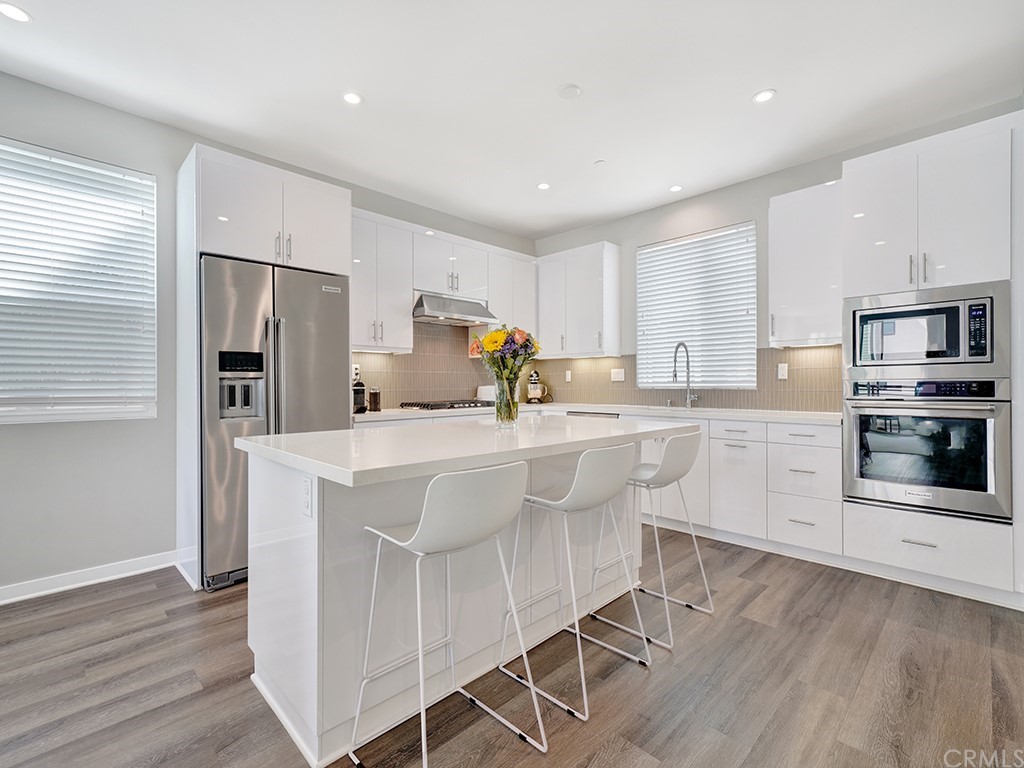 604 Malibu Costa Mesa, CA 92627 - Photo 6 of 40 a kitchen with stainless steel appliances a microwave a stove a sink dishwasher a refrigerator and white cabinets with wooden floor
