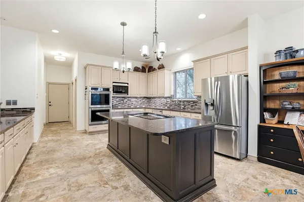 a kitchen with stainless steel appliances granite countertop a stove a sink a refrigerator and a wooden cabinets