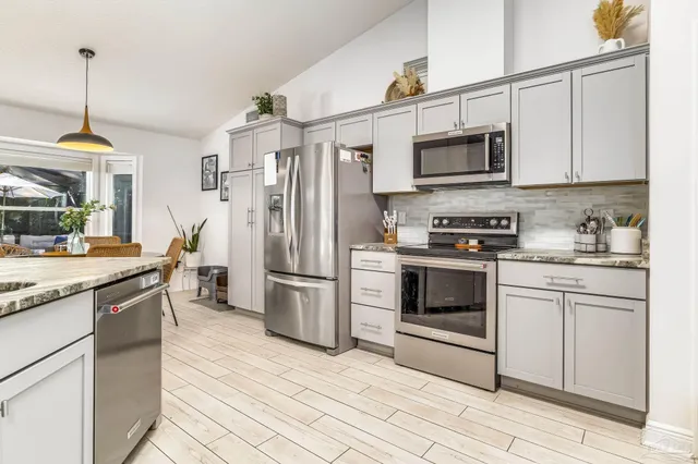 a kitchen with stainless steel appliances granite countertop a refrigerator a stove top oven a sink and dishwasher