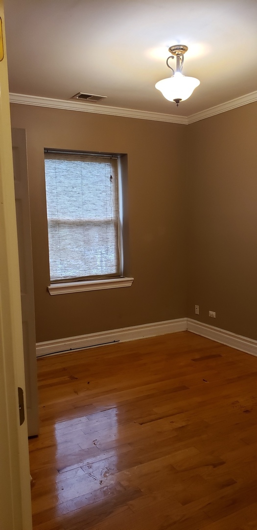 917 East 78th Street, Unit 101W Chicago, IL 60619 - Photo 7 of 8 a view of an empty room with wooden floor and a window