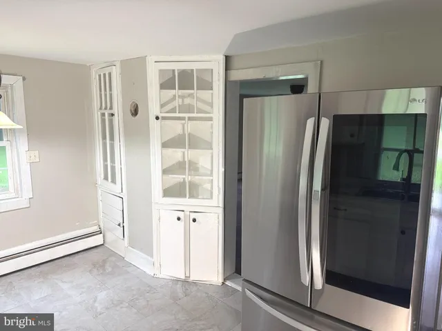 a view of a refrigerator in kitchen and wooden floor in a room