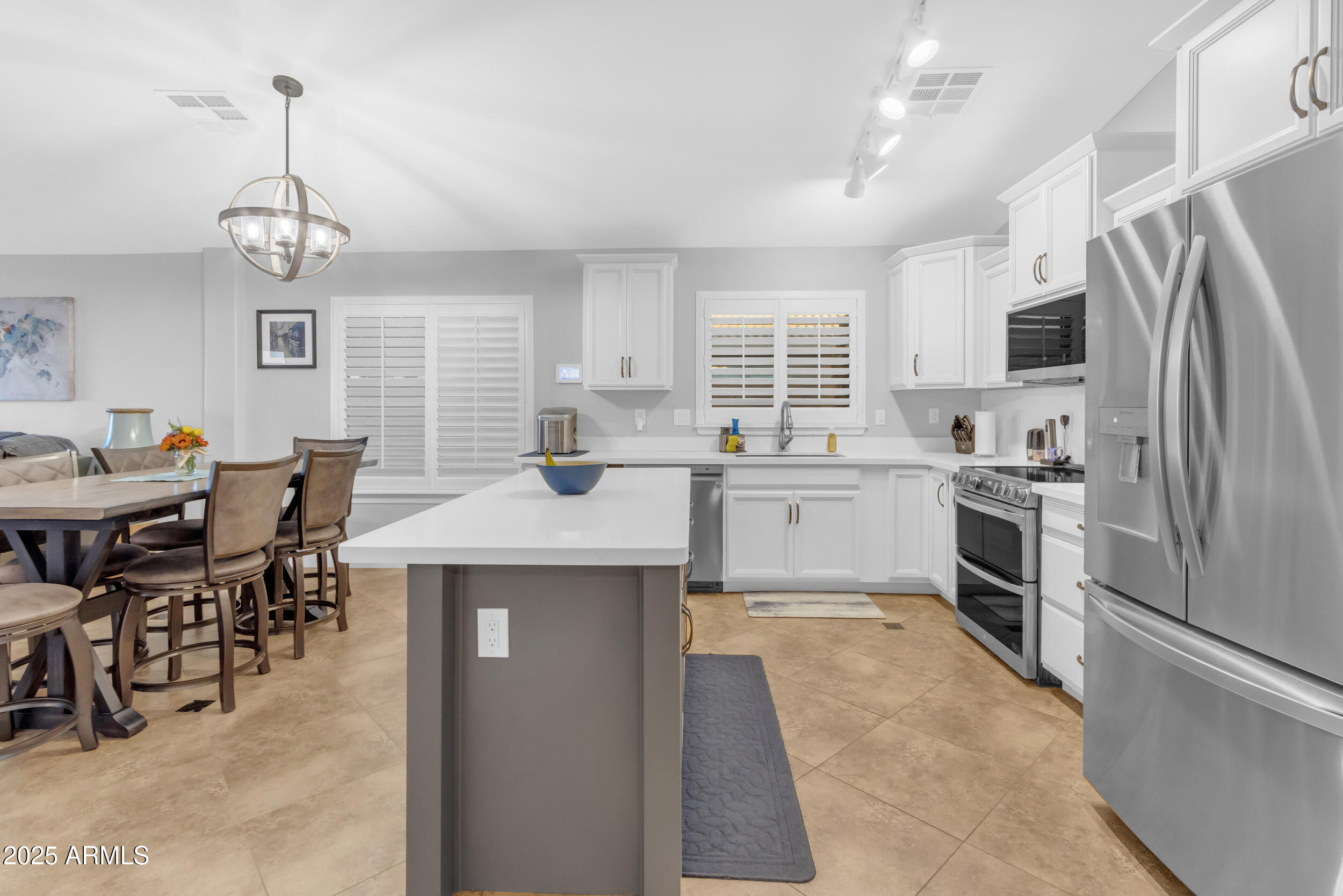13438 West Redfield Road Surprise, AZ 85379 - Photo 19 of 75 a kitchen with stainless steel appliances granite countertop a sink dishwasher a refrigerator a stove a dining table and chairs with wooden floor