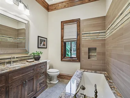 a bathroom with a granite countertop sink a toilet a mirror and shower